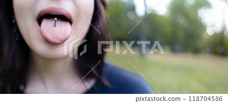 Beautiful woman sticking out her tongue and showing her piercing Beautiful woman sticking out her tongue and showing her piercing 118704586