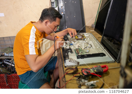 Asian man using soldering iron to repair led tv at service station Asian man using soldering iron to repair led tv at service station 118704627