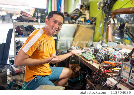 Asian male technician with hand gesture offering something Asian male technician with hand gesture offering something 118704629