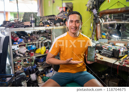 Asian electronics repairman smiles as he shows a cell phone screen 118704675