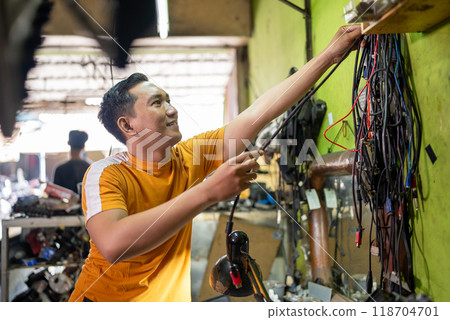 repairman takes a cable from the wall in the electronics repair room 118704701