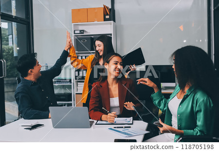 Young corporate employees sitting in office looking at laptop screen reading good news excited happy team diverse people celebrating victory win command success excellent result professional teamwork 118705198