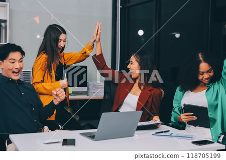 Young corporate employees sitting in office looking at laptop screen reading good news excited happy team diverse people celebrating victory win command success excellent result professional teamwork 118705199