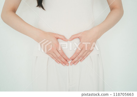 Woman making a heart shape with her hands on her stomach 118705663