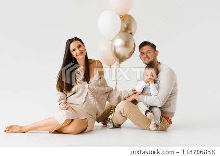 Happy family with a one year old birthday boy are sitting on the floor next to balloons 118706838