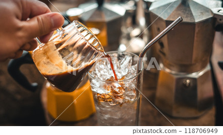 Making iced coffee. Pouring coffee into a glass with ice. Making iced coffee. Pouring coffee into a glass with ice. 118706949