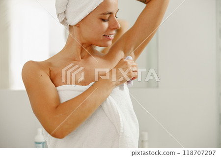 A woman is meticulously shaving her underarm area after enjoying a refreshing shower A woman is meticulously shaving her underarm area after enjoying a refreshing shower 118707207