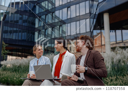 Engaging in Team Collaboration Outdoors While Using Laptops and Enjoying Coffee Beverages 118707358