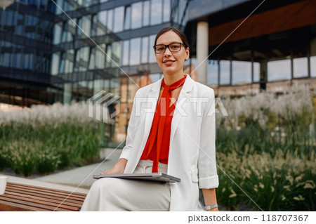 Confident Businesswoman in a Bustling Urban Setting with Her Laptop and Ambitious Goals 118707367