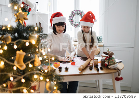 Mother and daughter baking Christmas cookies together at home Mother and daughter baking Christmas cookies together at home 118709589