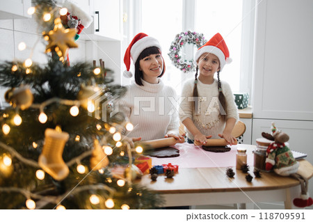 Mother and daughter baking Christmas cookies together at home Mother and daughter baking Christmas cookies together at home 118709591