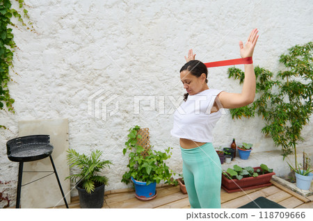 Woman exercising with resistance band in peaceful garden setting 118709666