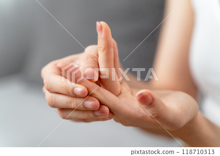 Closeup young woman sitting on sofa holds her wrist. hand injury, feeling pain. Health care. 118710313