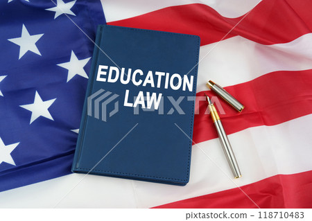On the US flag lies a pen and a book with the inscription - EDUCATION LAW On the US flag lies a pen and a book with the inscription - EDUCATION LAW 118710483