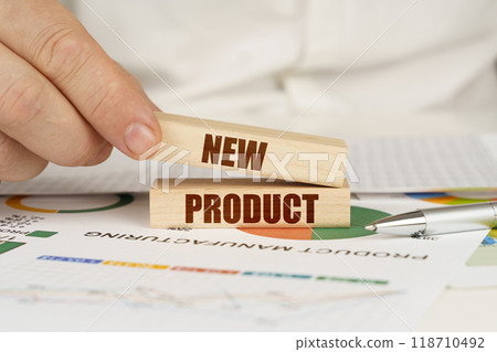 On the table are business charts and diagrams in the hands of a wooden block with the inscription - NEW PRODUCT 118710492