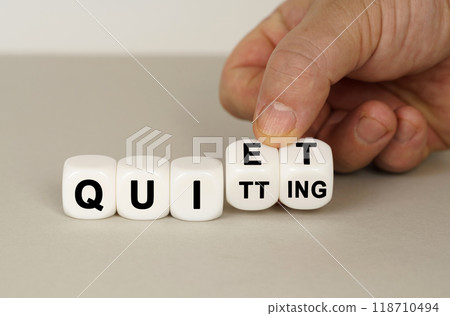 On a gray surface are white cubes with the inscription - QUIET or QUITTING 118710494