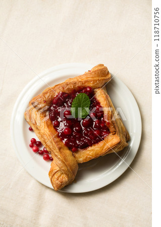 A delicious dessert, puff pastry cake with berry filling. Cranberry dessert on a light color 118710756