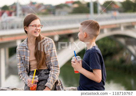 A boy and a girl are having fun together and drinking bubble tea by the river A boy and a girl are having fun together and drinking bubble tea by the river 118710767