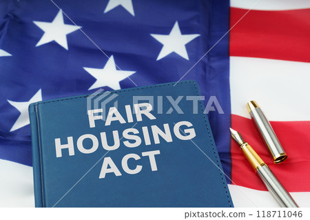 On the US flag lies a pen and a book with the inscription - FAIR HOUSING ACT On the US flag lies a pen and a book with the inscription - FAIR HOUSING ACT 118711046