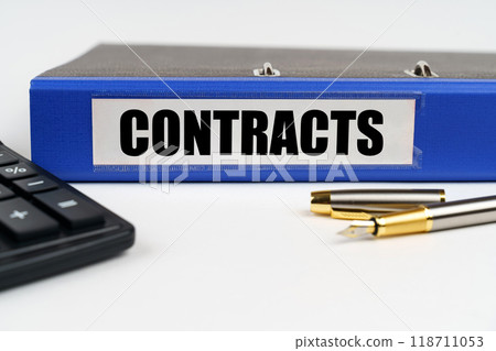 On a white surface, a calculator, a pen and a folder with the inscription - contracts On a white surface, a calculator, a pen and a folder with the inscription - contracts 118711053