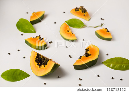 Fruit background made of pieces of ripe papaya with green leaves on a white background 118712132