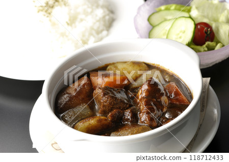 A set of beef stew with chunks of meat and vegetables, rice and salad 118712433