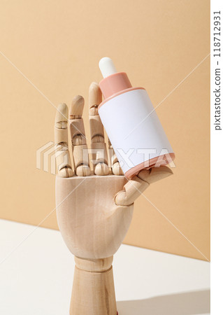 A cosmetic bottle in a mannequin's wooden hand 118712931