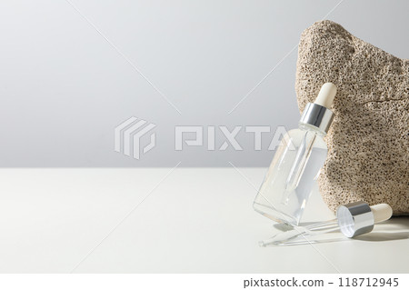 Cosmetic oil in a transparent bottle with a stone 118712945