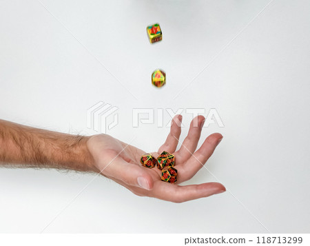 Tossed colorful dice in mid-air over hand against white background 118713299