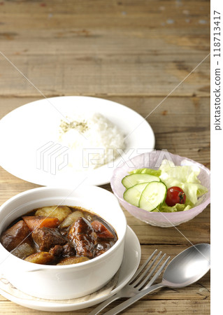 A set of beef stew with chunks of meat and vegetables, rice and salad A set of beef stew with chunks of meat and vegetables, rice and salad 118713417