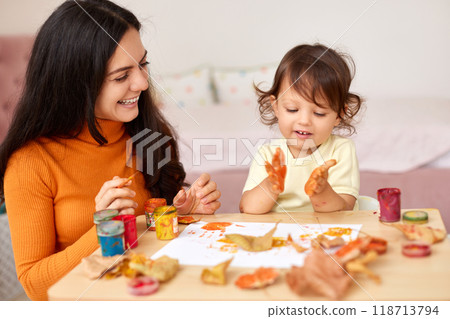 happy little child girl and mom spending good time painting hands and autumn yellow leaves together 118713794