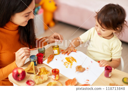 little child girl and mother spending good time painting hands and autumn yellow leaves together. kid leaves yellow handprints. little child girl and mother spending good time painting hands and autumn yellow leaves together. kid leaves yellow handprints. 118713848
