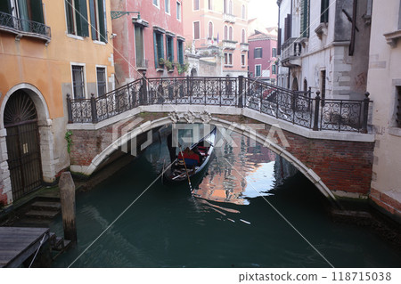Gondola in Venice passing under a bridge over a narrow waterway 118715038