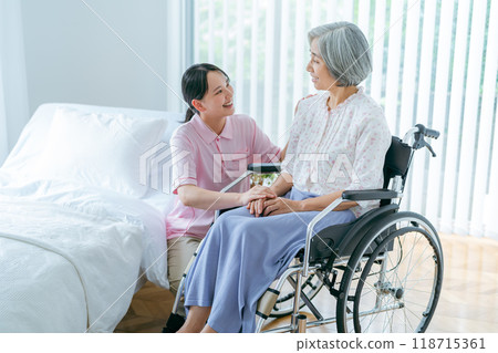 Senior woman living in a nursing home and a young caregiver Senior woman living in a nursing home and a young caregiver 118715361