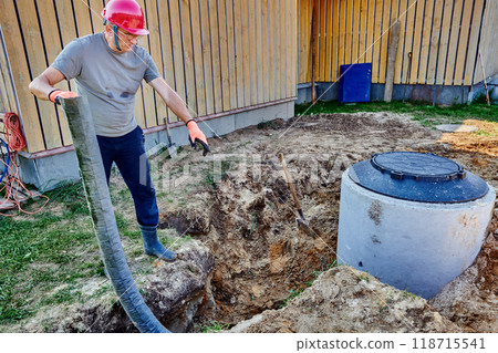 Worker lays perforated drainage pipe in an absorption trench. 118715541