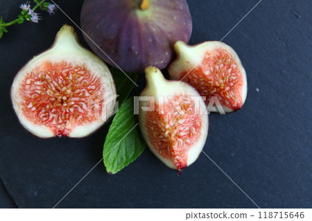 Purple figs on a black stone plate. Photo, background with fresh, juicy, ripe tropical fruits. Suitable for depicting vegetarian and raw, healthy food, harvest. Symbol of abundance and enlightenment. Purple figs on a black stone plate. Photo, background with fresh, juicy, ripe tropical fruits. Suitable for depicting vegetarian and raw, healthy food, harvest. Symbol of abundance and enlightenment. 118715646