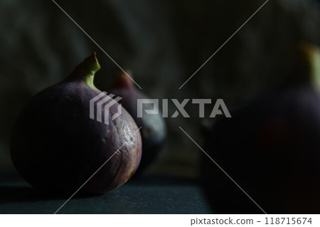 Purple figs on a black stone plate. Photo, background with fresh, juicy, ripe tropical fruits. Suitable for depicting vegetarian and raw, healthy food, harvest. Symbol of abundance and enlightenment. 118715674