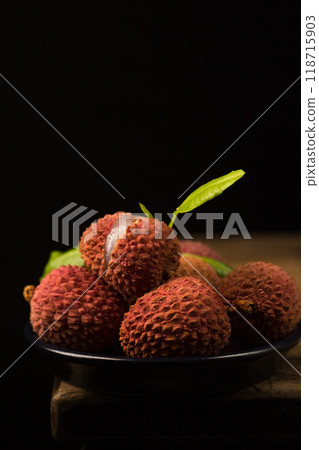 Small ripe tropical lychee berries on a black plate in a minimalist style, low key 118715903
