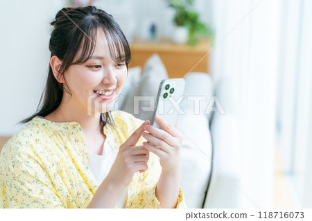 在房間裡操作智慧型手機的年輕女子 118716073