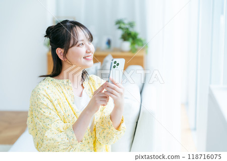 在房間裡操作智慧型手機的年輕女子 118716075