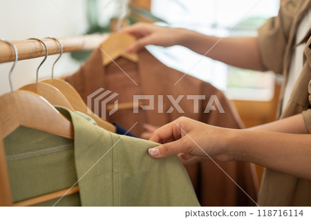 Females selecting clothes from a rack, enjoying their shopping experience together. Females selecting clothes from a rack, enjoying their shopping experience together. 118716114