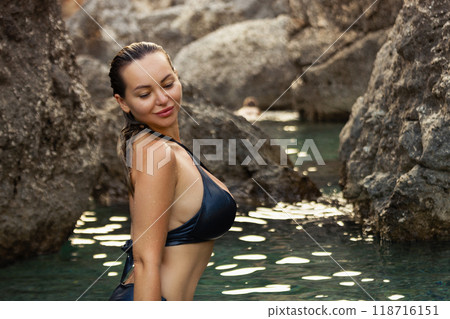 Beautiful girl in a black swimsuit in a blue lagoon among the rocks Beautiful girl in a black swimsuit in a blue lagoon among the rocks 118716151