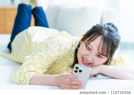 A young woman operating a smartphone in a room A young woman operating a smartphone in a room 118716508
