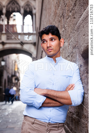 Young European guy in blue shirt walking around city 118716783