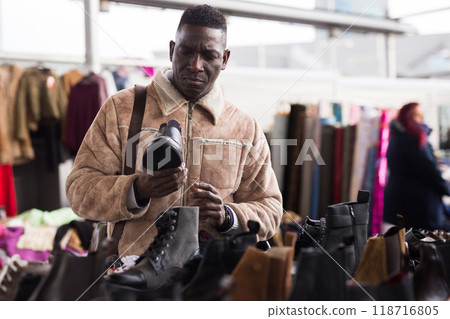 Man looks at used shoes at a flea market 118716805