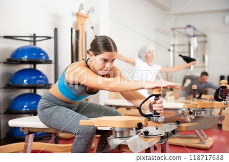 Young woman stretching her arms using pilates machine Young woman stretching her arms using pilates machine 118717688