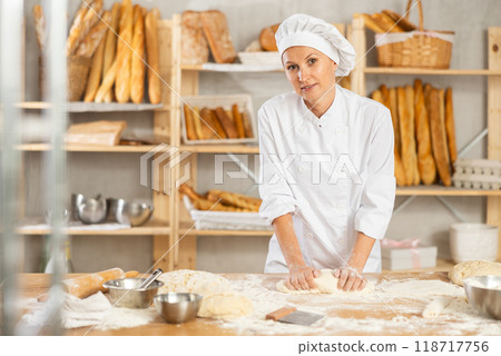 Woman works in bakery as baker, kneads dough, works with flour. 118717756