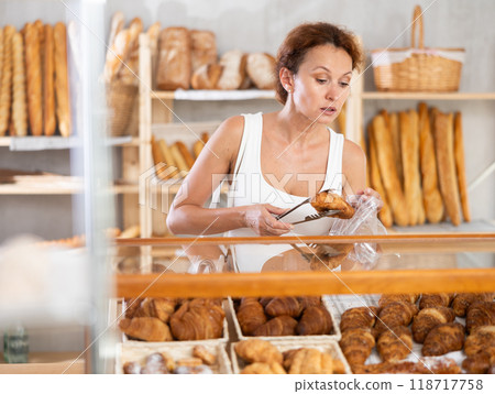 Woman packs croissant in plastic disposable bag in bakery shop 118717758