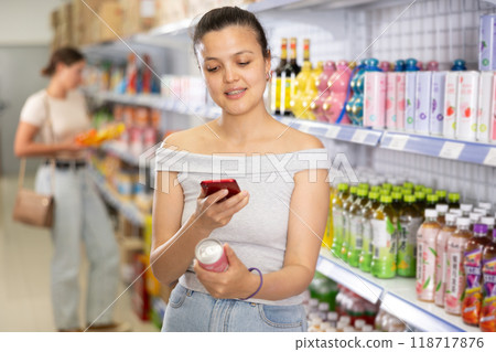 Girl reads QR code from aluminum can of drink in chinese supermarket 118717876
