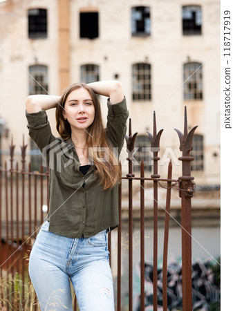 Woman posing near fence against abandoned building Woman posing near fence against abandoned building 118717919